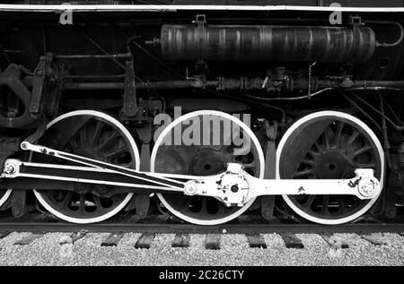 Die großen, weiß umrandenen Räder einer alten Dampfmaschine in schwarz und weiß. Stockfoto