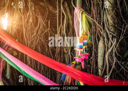 Fünf Farben Stoff umwickeln den Baum und Girlande auf Atemwurzel des banyan Baum mit Fackel Licht. Der Glaube der Thailänder. Möglichkeiten zum Schutz von Th Stockfoto
