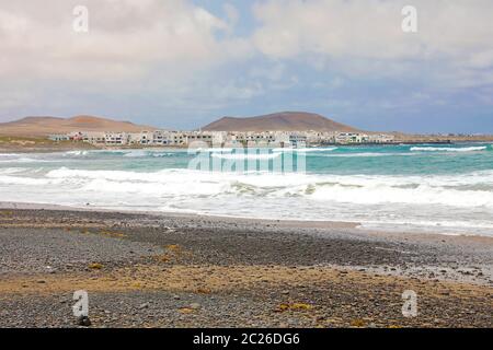 LANZAROTE, SPANIEN - 19. APRIL 2018: Caleta de Famara Strand und Dorf auf dem Hintergrund, Lanzarote, Kanarische Inseln Stockfoto