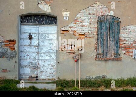 Verlassene Gebäude mit Strohbesen lehnt an alten beschädigten Ziegelmauer, Lombardei, Italien Stockfoto