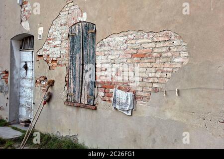 Verlassene Gebäude mit Strohbesen lehnt an alten beschädigten Ziegelmauer, Lombardei, Italien Stockfoto