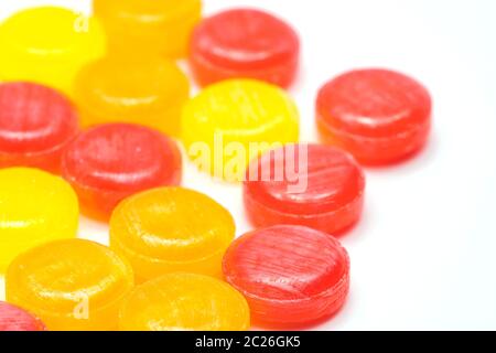 Medizinische Lutschtabletten zur Linderung von Husten, Halsschmerzen und Rachenreizungen isoliert auf weißem Hintergrund. Husten und Erkältungen fallen. Bunte Hustenpastille. Rote, orange und gelbe runde Süßigkeiten oder Süßigkeiten. Stockfoto