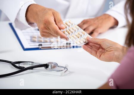 In der Nähe von männlicher Arzt Hand geben Pillen in Blisterpackungen zu weiblichen Patienten in der Klinik Stockfoto