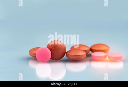 Selektiver Fokus auf orange und pink, runde Tabletten mit Schatten auf farbverlauf Hintergrund. Pharmazeutische Industrie. Apotheke Produkte. Vitamine und suppleme Stockfoto