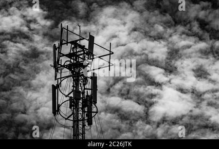 Schwarz-weiß Bild von Telekommunikation Turm gegen den grauen Himmel und weißen Wolken. Antenne am dunklen Himmel Hintergrund. Radio und Sat-Pol. Commun Stockfoto
