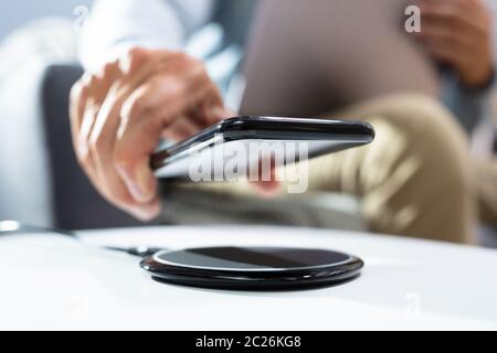 Man Aufladen Smartphone mithilfe des Wireless Charging Pad zu Hause Stockfoto