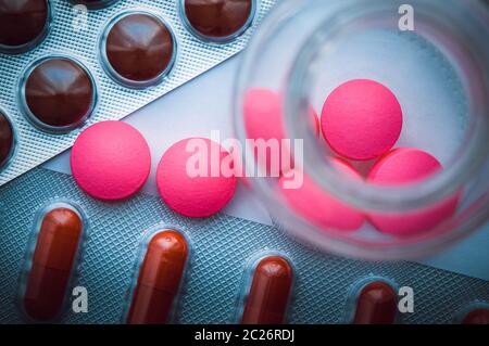 Blisterpackungen mit bunten Tabletten und rosa Pillen sind aus Glas auf einem weißen Hintergrund blau gegossen. Der Blick von oben Stockfoto