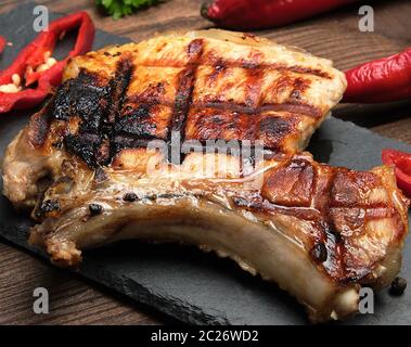 Stück gebratenes Schweinefilet auf ein Knochen liegt auf einem schwarzen Brett, saftiges Fleisch, Nahaufnahme Stockfoto