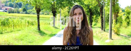 Aktive fröhliche Frau Anhalten nach einem Durchlauf in einem Park an einem sonnigen Tag. Freundlich lächelnde Mädchen an der Kamera in einem Park auf Frühling oder Sommer. Stockfoto