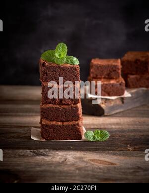Stapel von quadratische Stücke von gebackenen brownie Torte auf einem Holzbrett, Grün mint Sprig oben Stockfoto