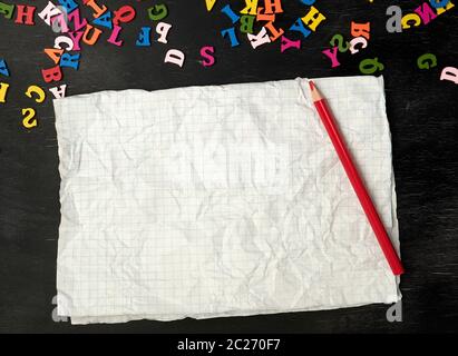 Zerknittertes Stück Papier von einer Schule Notebook in einem Käfig auf einem schwarzen Hintergrund, Konzept Zurück zur Schule Stockfoto