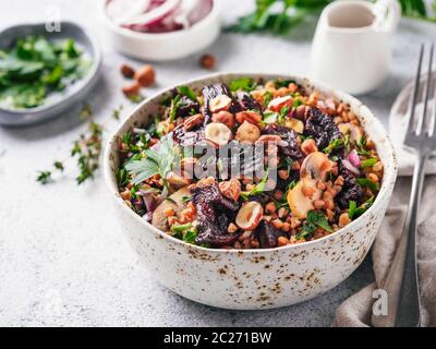 Warme Buchweizen und Rote-Bete-Salat auf grauem Hintergrund. Vegetarische Ernährung Idee und Rezept-Salat mit roter Bete, Buchweizen, Champignons, Zwiebeln, frischen Kräutern, h Stockfoto