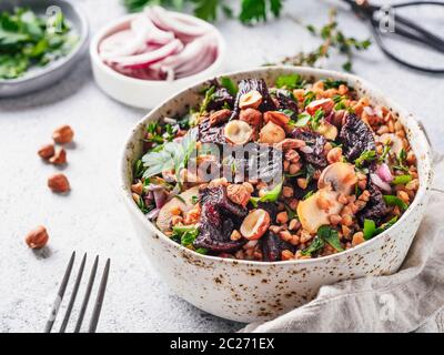 Warme Buchweizen und Rote-Bete-Salat auf grauem Hintergrund. Vegetarische Ernährung Idee und Rezept-Salat mit roter Bete, Buchweizen, Champignons, Zwiebeln, frischen Kräutern, h Stockfoto