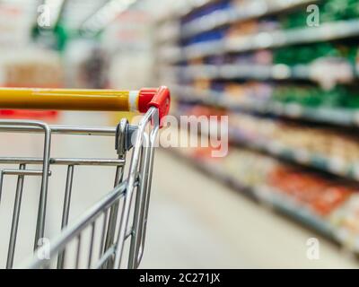 Warenkorb im Supermarkt. Teil der Einkaufsbahn im Supermarkt Gang. Verschwommene Regale im Lebensmittelgeschäft und Trolley. Kopieren Sie Platz für Text oder desi Stockfoto