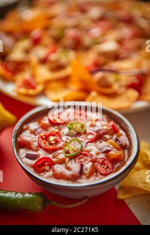 Nahaufnahme von heißen Tomaten Dip in Keramik-Schüssel mit verschiedenen frisch zubereiteten mexikanischen Speisen Stockfoto