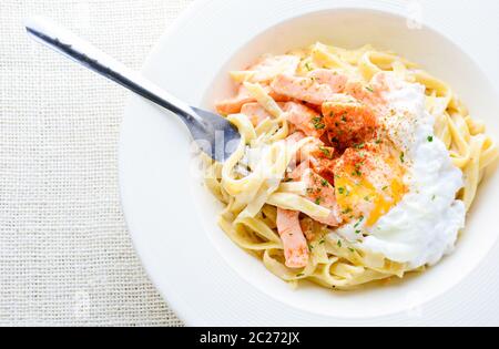 Fettucine mit Lachs, Ei und Parmesan, auf weiße Platte serviert. Stockfoto