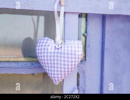 Karierten Herzen aus Stoff mit getrockneten Lavendelblüten in Pastelllila, die von einem alten Holzfenster gefüllt Stockfoto