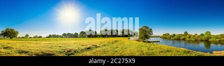 Landschaft im Sommer mit Bäumen, Wiesen, Fluss und Sonne Stockfoto