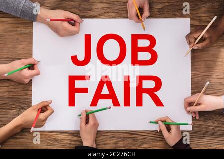 Einen erhöhten Blick auf Geschäftsleute Hände Schreiben mit Bunte Bleistifte auf Job Fair Papier Stockfoto