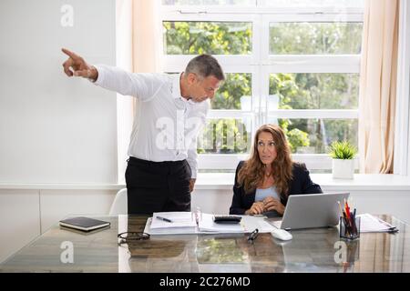 Wütend Reife Geschäftsmann Feuern weiblichen Angestellten im Büro umgekippt Stockfoto
