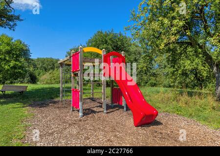 Klettergerüst für Kinder mit roter Rutsche im Sommer in einem Park Stockfoto