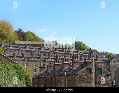 Straßen von terrassenförmigen Steinhäusern auf einem Hügel umgeben von Bäumen mit einem blauen Sommerhimmel in hebden Brücke West yorkshire Stockfoto