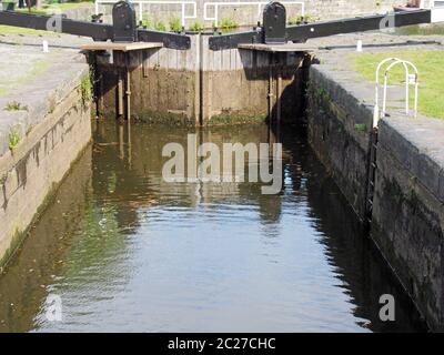 Eine Nahaufnahme von alten geschlossenen hölzernen Schleusentoren am calder- und Absteinschiffungskanal in brighouse spiegelte sich im Wasser wider Stockfoto