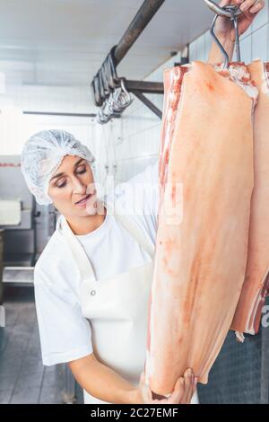 Metzgerin, die Fleisch für die weitere Verwendung und Verarbeitung schneidet Stockfoto