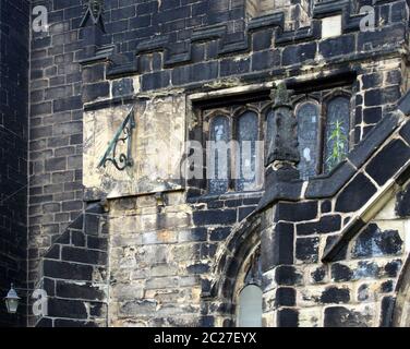 Eine Vollbildaufnahme von alten Steinarbeiten Glasfenster und eine Sonnenuhr auf der mittelalterlichen Kirche von St. johannes dem täufer in Stockfoto