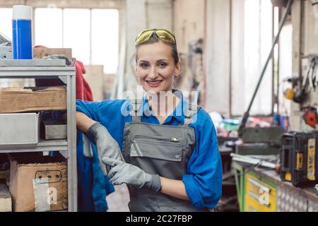 Fröhliche Frau Arbeiter in Metall-Werkstatt Blick in die Kamera Stockfoto