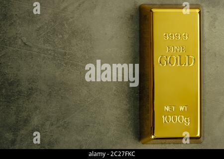 Masseln aus reinem Gold Metal bullion auf einem grauen strukturierten Hintergrund Stockfoto