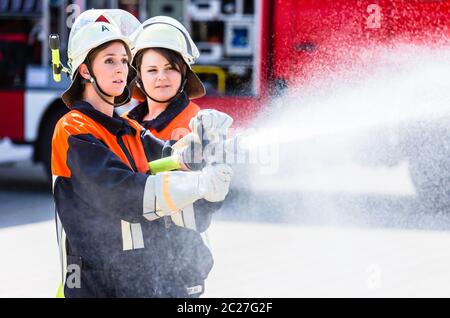 Feuerwehrinnen spucken Wasser, um Feuer zu löschen Stockfoto