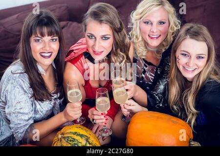 Junge und schöne Frau lustig und gruselig posiert während Toasten mit Ihren besten Freunden während Halloween Kostüm Party Stockfoto