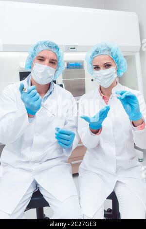 Wissenschaftler in biotech Labor mit der Pipette und der Probe Teller schauen in die Kamera Stockfoto