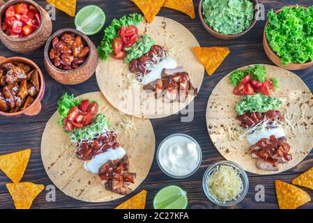 Tacos mit Füllungen auf dem hölzernen Tisch Stockfoto