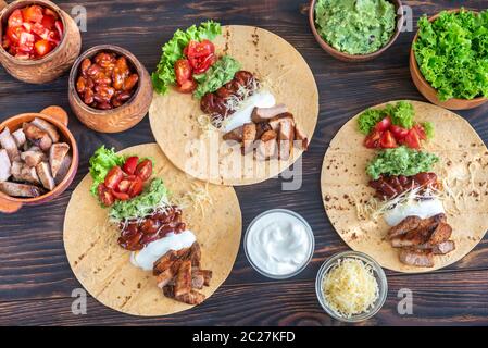 Tacos mit Füllungen auf dem hölzernen Tisch Stockfoto