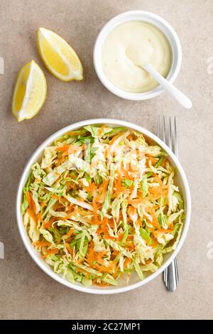 Krautsalat aus frisch geschreddertem Weißkohl und geriebener Karotte mit hausgemachtem Salat-Dressing auf Mayonnaise-Basis und Zitronenpfeilchen an der Seite, photogra Stockfoto