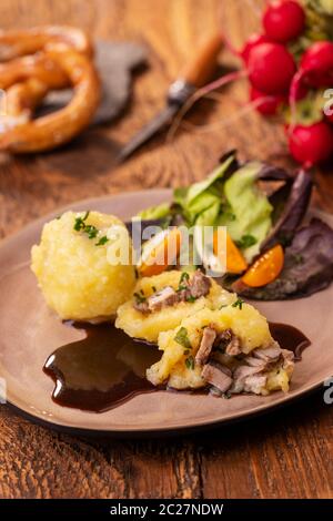 Gefüllte Kartoffelklöße mit Salat auf Holz Stockfoto