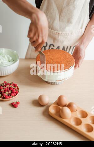 Ebenen des Menschen Hand Creme auf Kuchen, Kuchen Dekor. Und Biskuitteig. Stockfoto