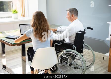 Deaktiviert Geschäftsmann sitzt mit seinem Partner mit Laptop über Schreibtisch im Büro Stockfoto