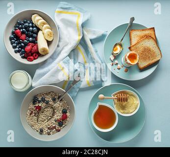 Frühstück serviert mit Haferflocken und Obst, gekochte Eier, Honig und Butter. Leckeren, gesunden Frühstück. Stockfoto