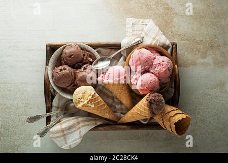 Eis Schaufeln mit Schokolade, Erdbeere und Vanille Aromen, Schaufelte sich bei Waffeln und Schalen Stockfoto