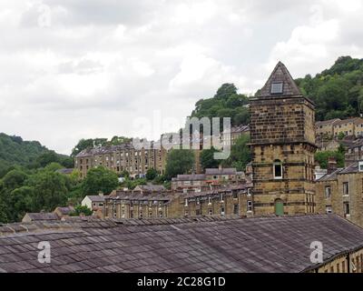 Blick auf die steilen Hangstraßen in hebden Brücke zwischen Sommerbäumen mit dem Turm der historischen Nussbaum Mühle gebaut Stockfoto