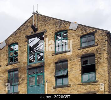 Das kaputte Dach und die kaputten Fenster in einem großen, ausgebrannten alten Industriegebäude nach einem Brand Stockfoto