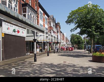 Menschen sitzen in Cafés im Freien und gehen an Geschäften in der historischen lord Street Einkaufsgegend in southport merseyside vorbei Stockfoto