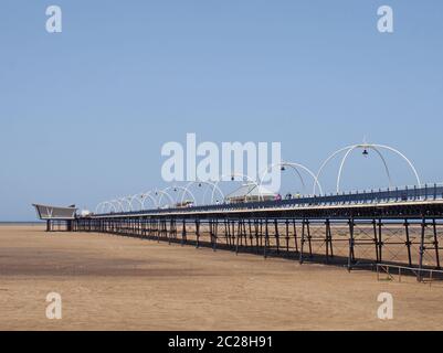 Menschen auf dem historischen Pier in southport merseyside mit dem Strand bei Ebbe an einem hellen Sommertag ausgesetzt Stockfoto