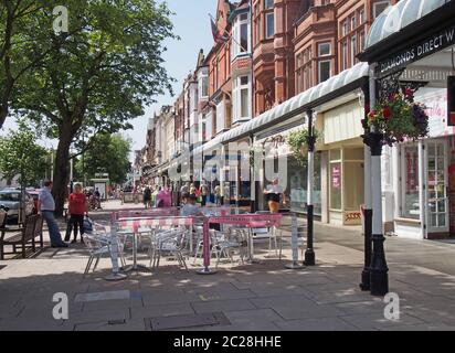 Menschen sitzen in Cafés im Freien und gehen an Geschäften in der historischen lord Street Einkaufsgegend in southport merseyside vorbei Stockfoto