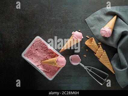 Frische von Softeis oder gefrorenen Joghurt mit Beeren Fruchtaromen. Obst Eis Schaufeln, geschöpft aus dem Behälter in die waffle Kegel mit einem silbernen Stockfoto