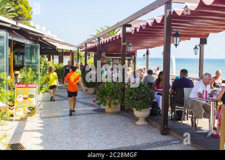 3. Oktober 2018 Patrons essen im terrassenförmig angelegten Gehweg Restaurant mit Blick auf Prai da Oura Strand in Albuferia Portugal an einem schönen heißen Nachmittag Stockfoto