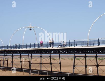 Menschen auf dem historischen Pier in southport merseyside mit dem Strand bei Ebbe an einem hellen Sommertag ausgesetzt Stockfoto